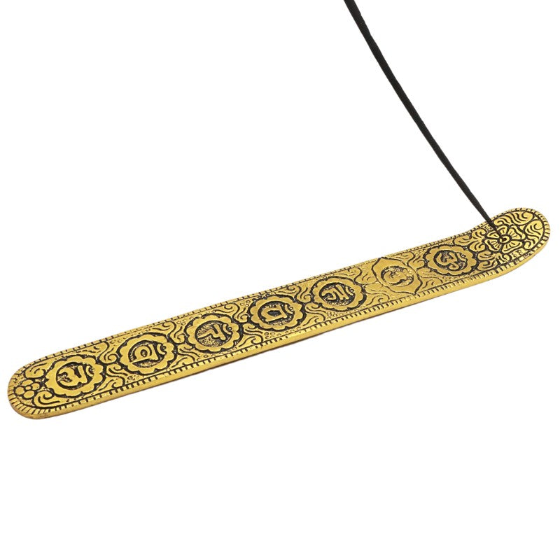incense stick in the top of an gold coloured aluminium incense burner with chakra symbols etched into top