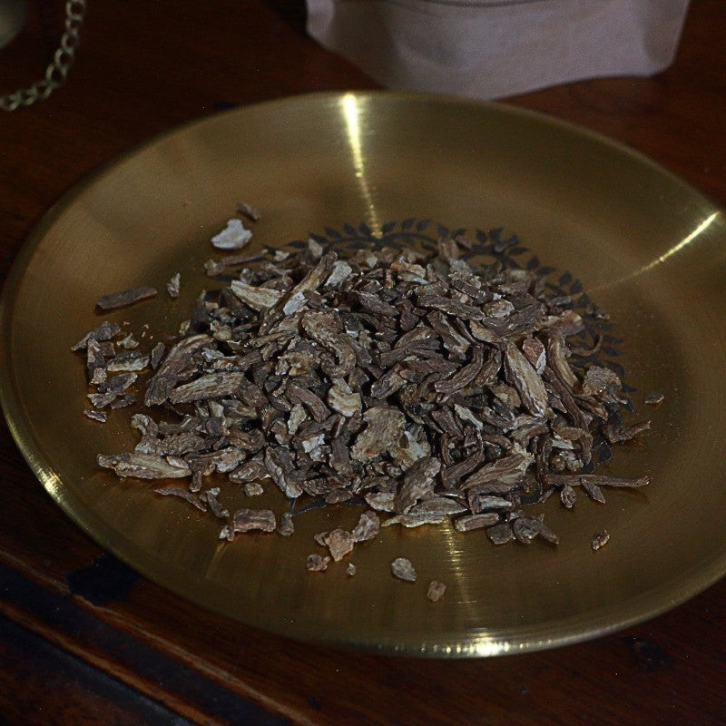 Dried herbs on a brass plate on a wooden surface
