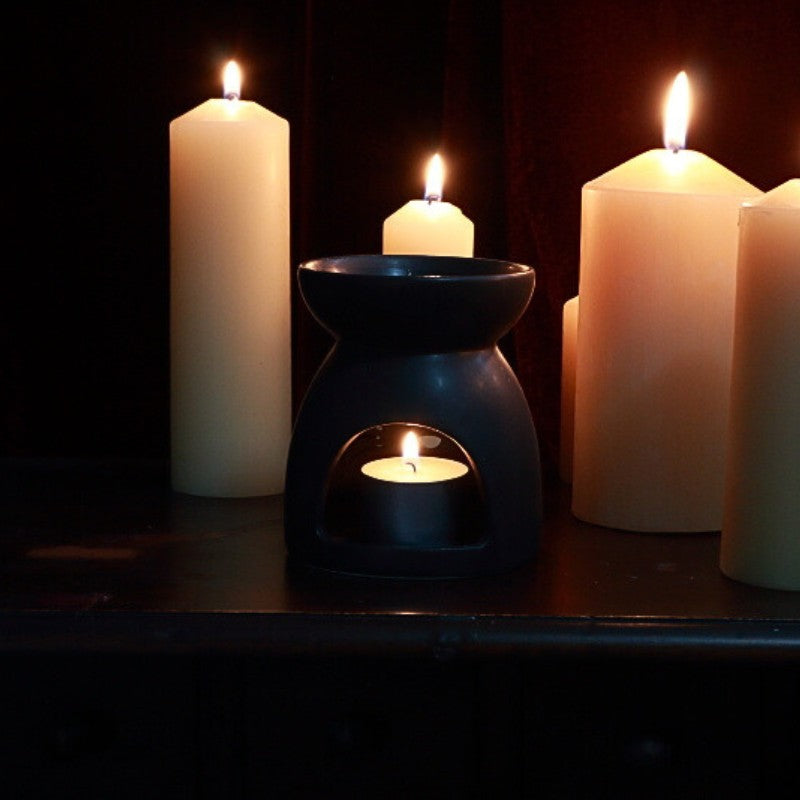 black oil burner. Lit beeswax pillar candles in the background.