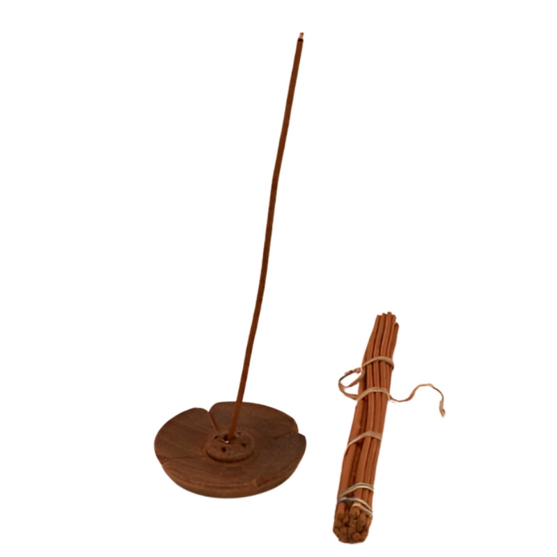 Round wooden carved incense holder- dark wood with a tibetan incense stick in the centre, next to a bundle of tibetan incense sticks