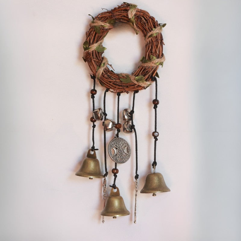Decorative wall hanging with a wreath and hanging bells on a plain background
