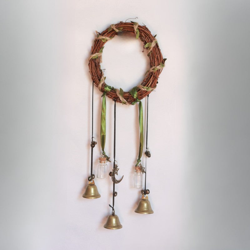 Decorative wall hanging with a vine wreath and hanging bells on a plain background