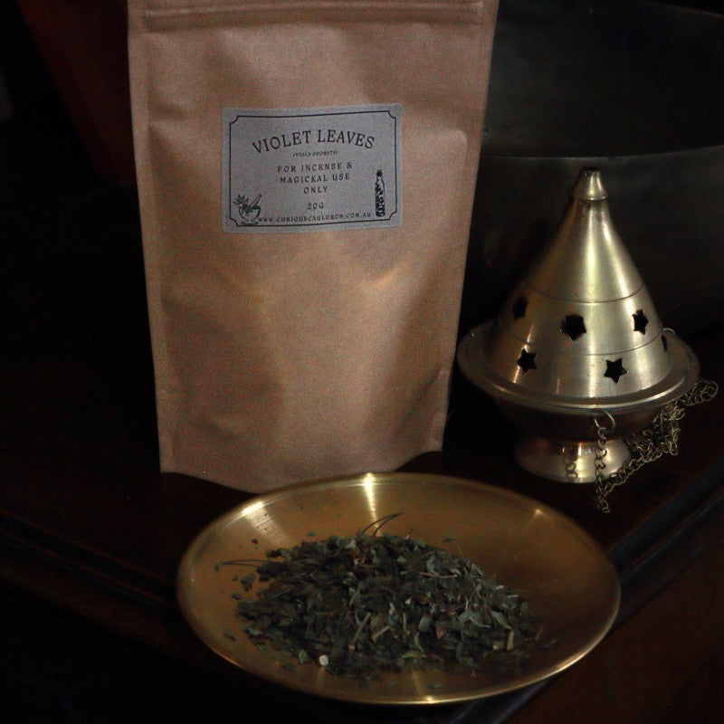 Bag of 'Violet Leaves' incense with a brass dish and cone incense burner on a dark background