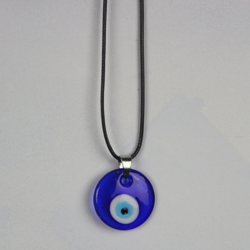 blue, white, light blue and black concentric circles formed into an eye shaped bead, hung on a black cord with a silver clasp. The necklace hangs on a light grey wall