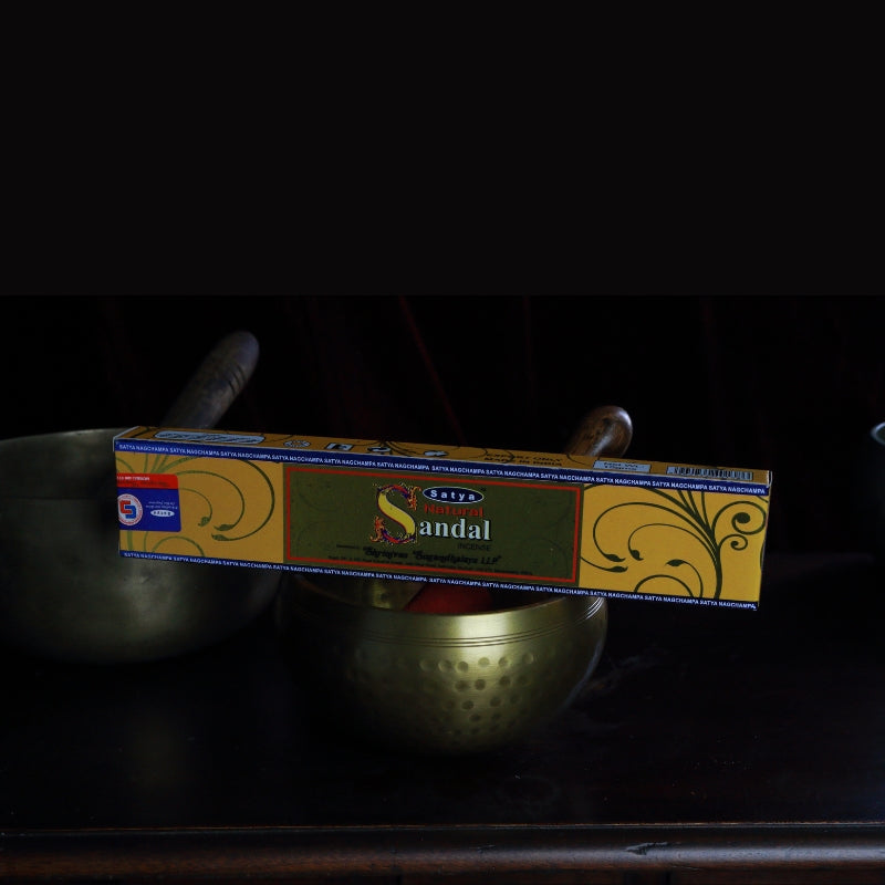 satya incense sticks sitting on a brass singing bowl