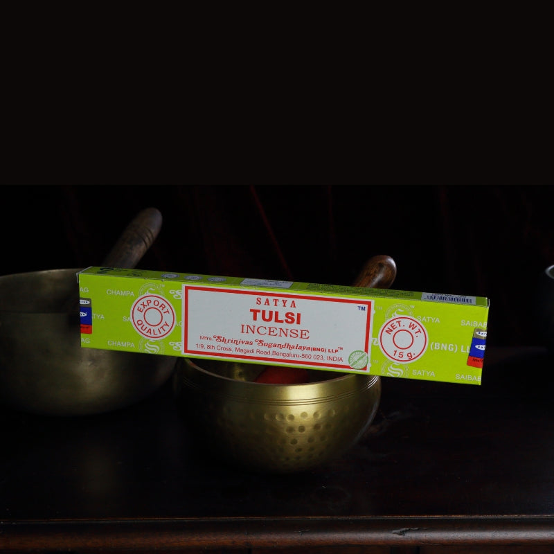 satya incense sticks sitting on a brass singing bowl