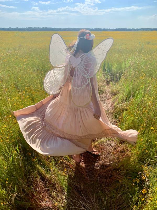 Girl dressed as fairybrunning through field