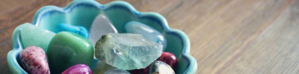 tumbled stones/ crystals in a blue bowl, on a wooden table