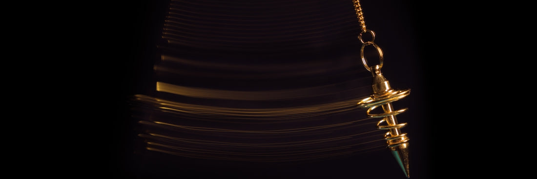 gold spiral pendulum swinging on black background