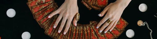 woman laying out red tarot cards on a table surrounded by white tea light candles