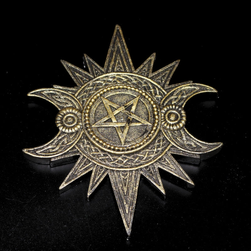 Gold coloured incense holder in the shape of a sun with a pentacle in the centre and two crescent moons at each side of the pentacle. An hole for an incense stick in the centre.