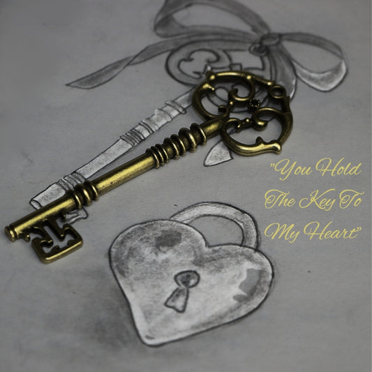 Gold skeleton key sitting atop a drawing of a key and padlock heart