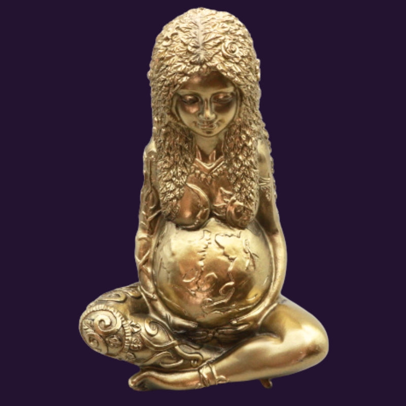gold statue of a woman with the earth as her pregnant stomach representing mother earth