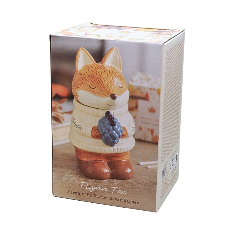 Ceramic oil burner & wax warmer figurine of a fox in a cream sweater holding blue grapes, shown in its retail packaging box.