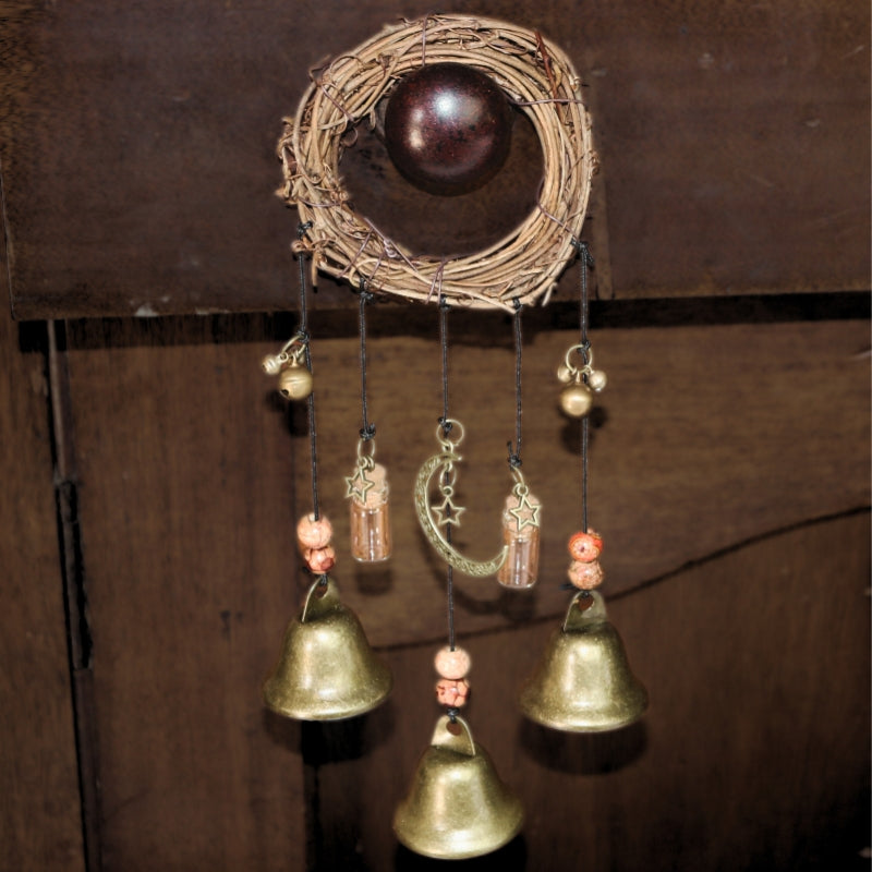 witches bells  consisting of a wreath with 3 brass bells attached by black string and beads., hanging on a cupboard door 