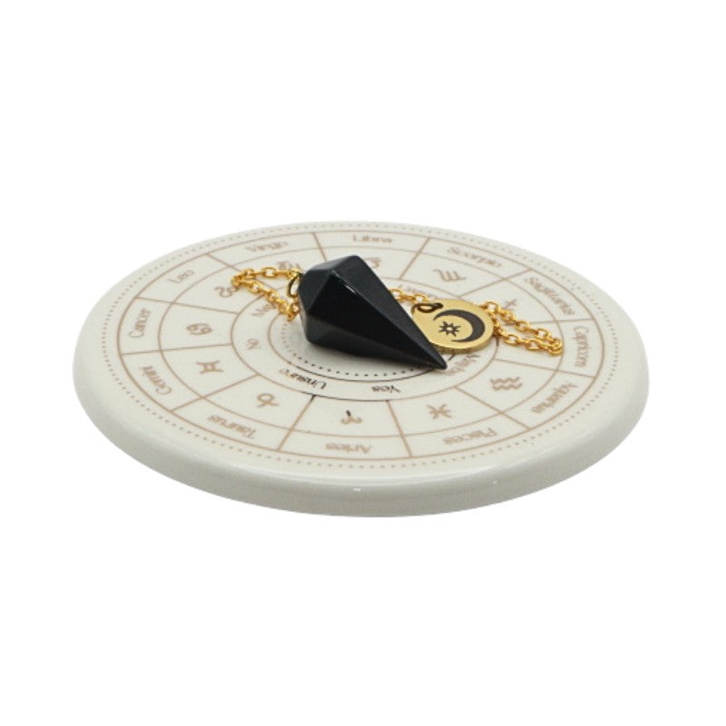 Black pendulum on a white circular astrological chart with zodiac signs.