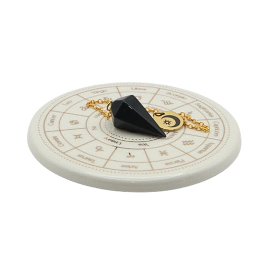 Black pendulum on a white circular astrological chart with zodiac signs.