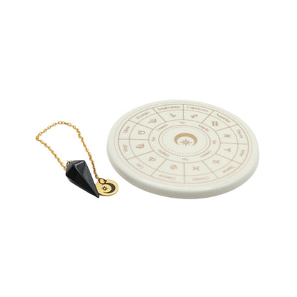 Decorative pendulum board with astrological symbols on a white background with an obsidian pendulum