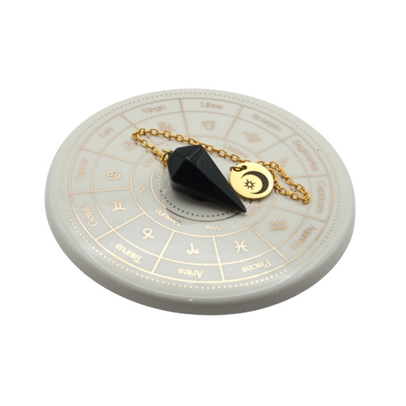 Black pendulum on a circular astrological chart with gold chain