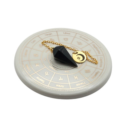 Black pendulum on a circular astrological chart with gold chain