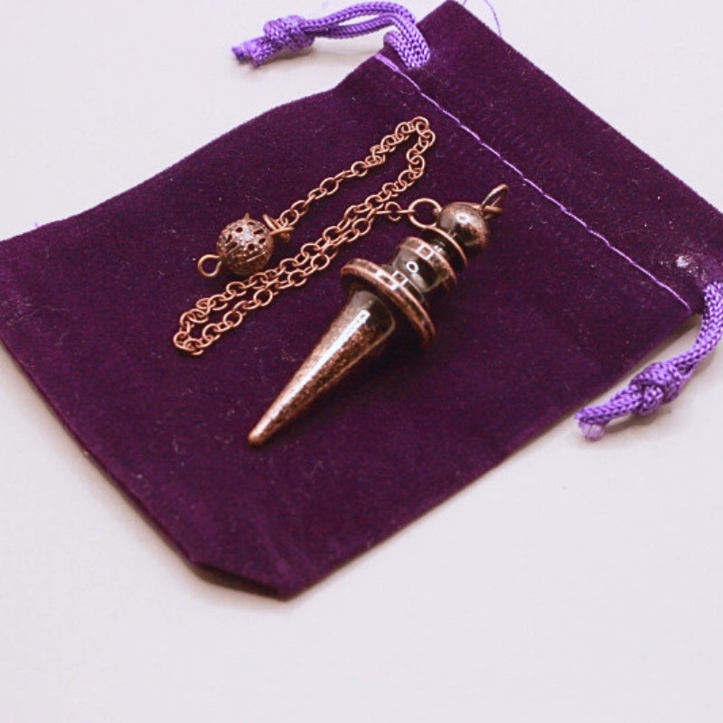 antique copper pendulum on purple velvet bag