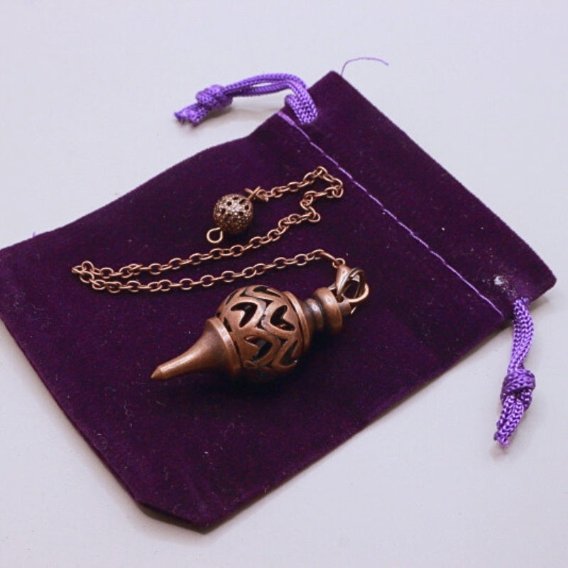 antique copper pendulum on purple velvet bag