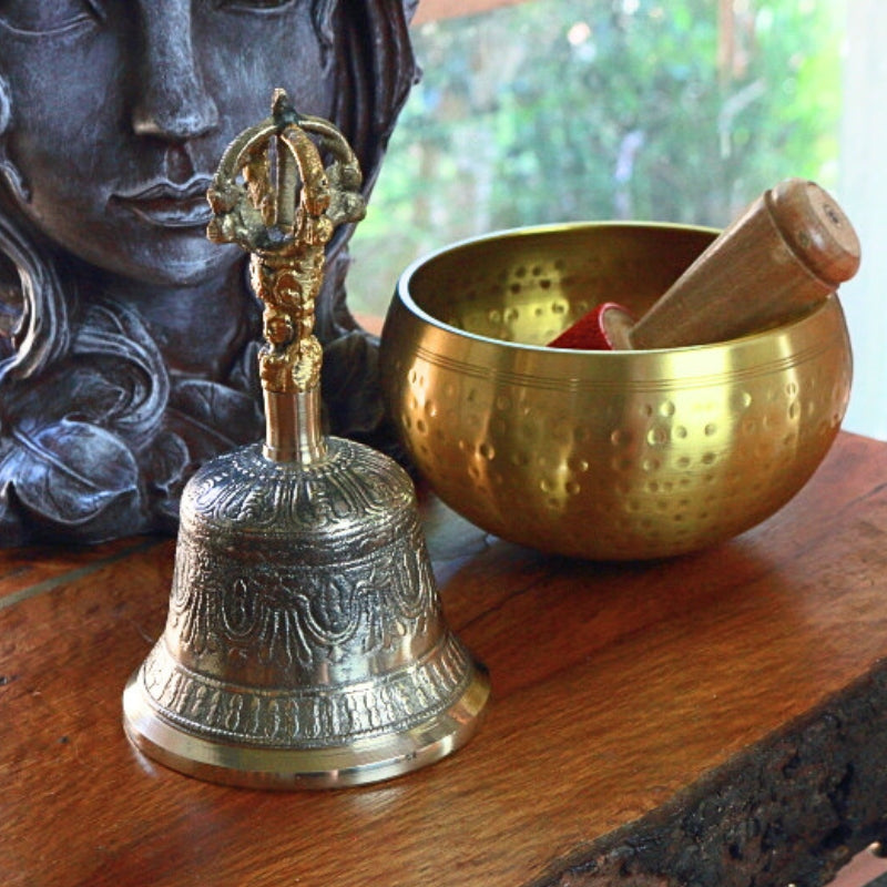 Tibetan Prayer Bell- Ghanta/ Altar Bell in front of a brass singing bowl and goddess plantar
