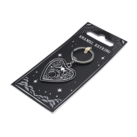 black and silver key chain the shape of a planchette on a black card background with witchy designs