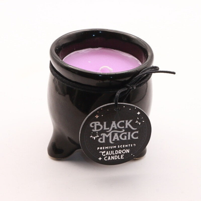 a coloured candle housed in a black ceramic cauldron