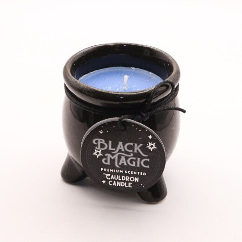 a coloured candle housed in a black ceramic cauldron