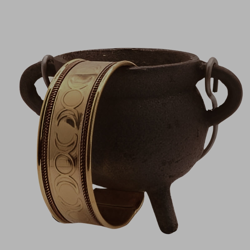 gold triple moon design cuff bracelet hanging off a cauldron