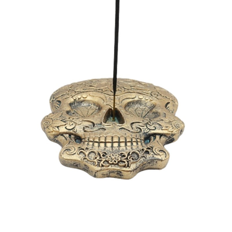 incense stick in a gold incense burner in a skull shape with floral designs