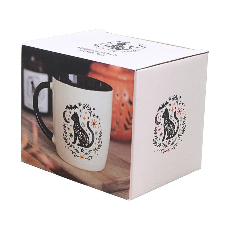packaging box featuring cream cup with black handle with an image of a black cat and black and orange floral design on a white background