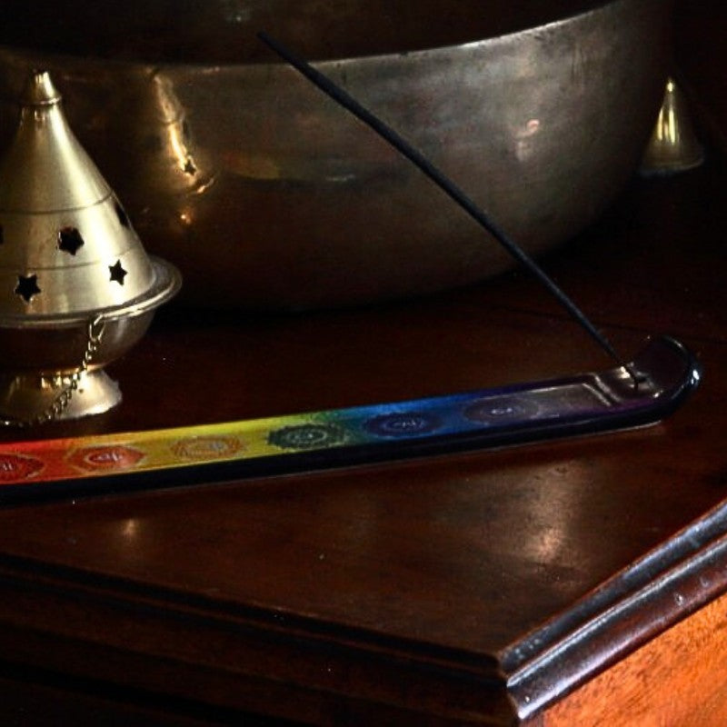 incense stick in a colourful chakra pattern ceramic incense holder on a wooden table