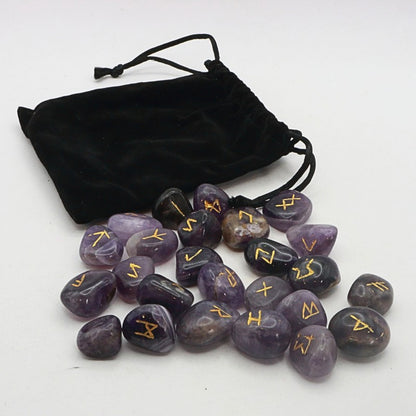 Set of purple stones with gold runes next to a black drawstring bag on a white background