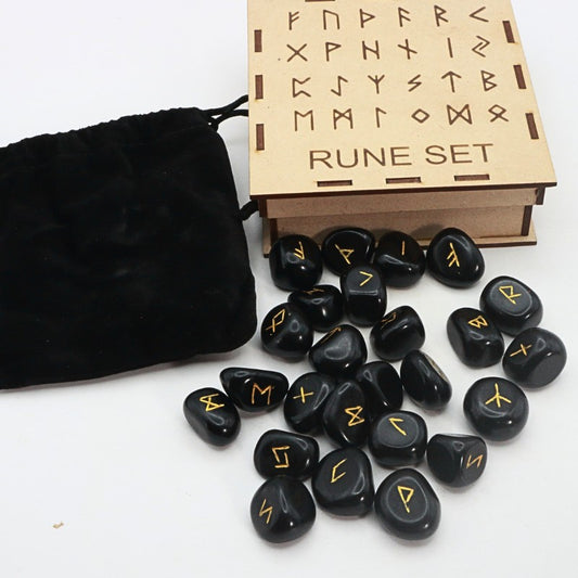 Rune set with black stones and wooden box on a white background