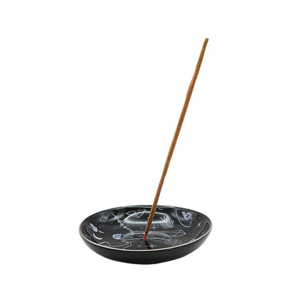 Black ceramic incense holder with a single incense stick on a white background