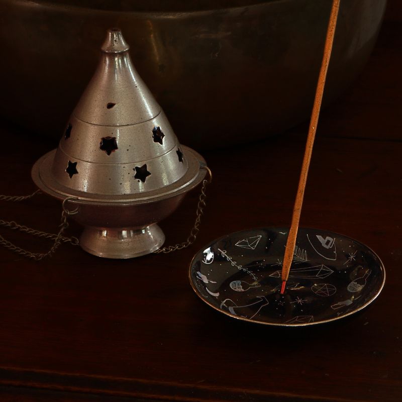 Incense burner with a single incense stick on a dark surface
