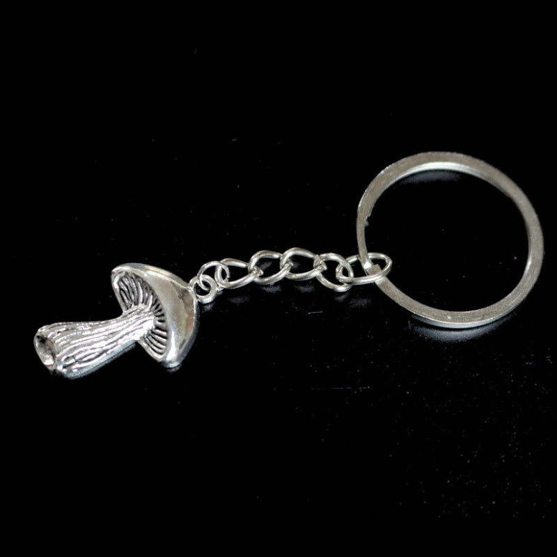 silver coloured key ring with a mushroom  joined to a silver ring by a silver chain on a black background