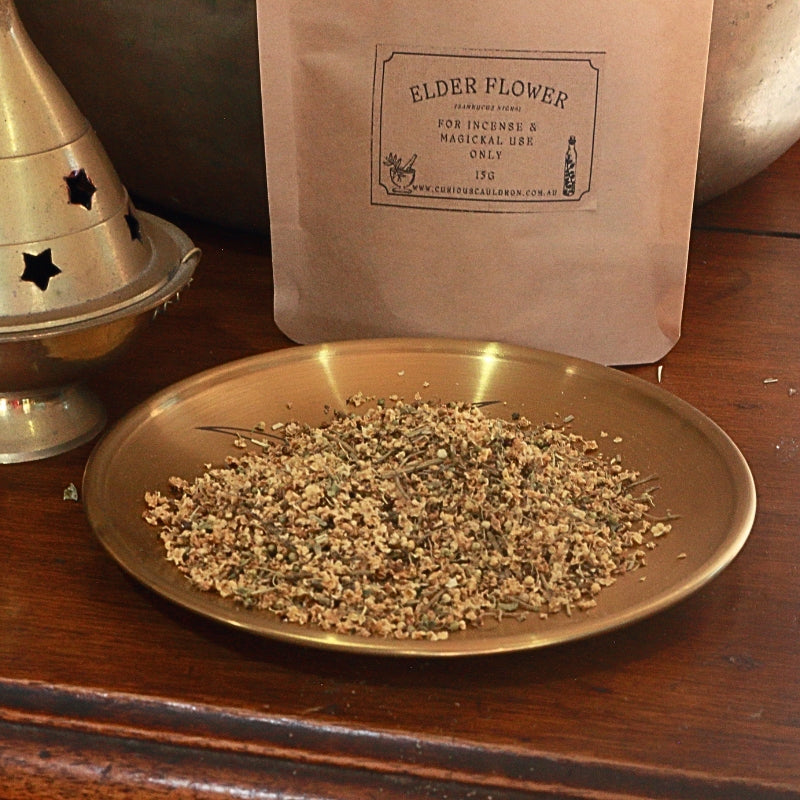 dried elder flowers on a gold plate in front of a paper bag with the label "elder flower"
