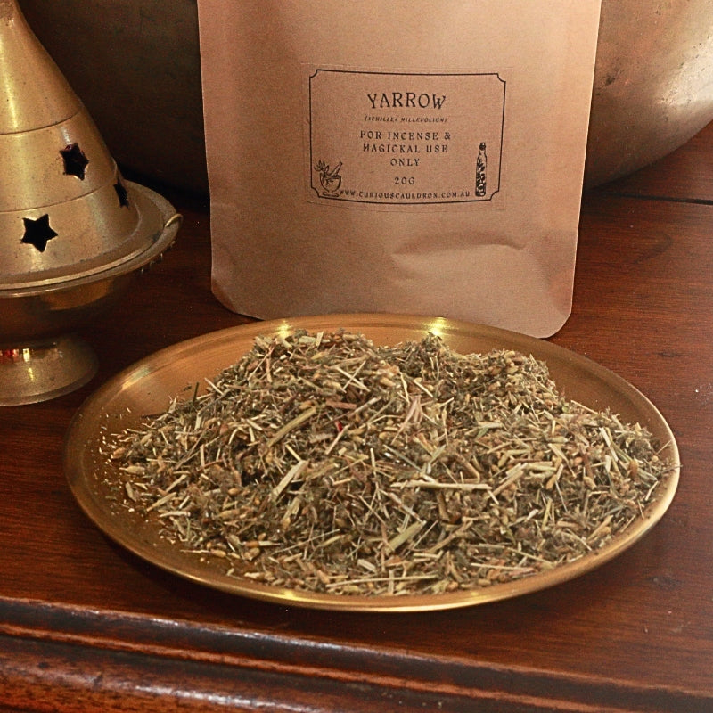 kraft paper bag with a label for "yarrow" and a gold plate in front of it with dried yarrow