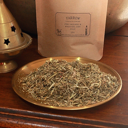 kraft paper bag with a label for "yarrow" and a gold plate in front of it with dried yarrow