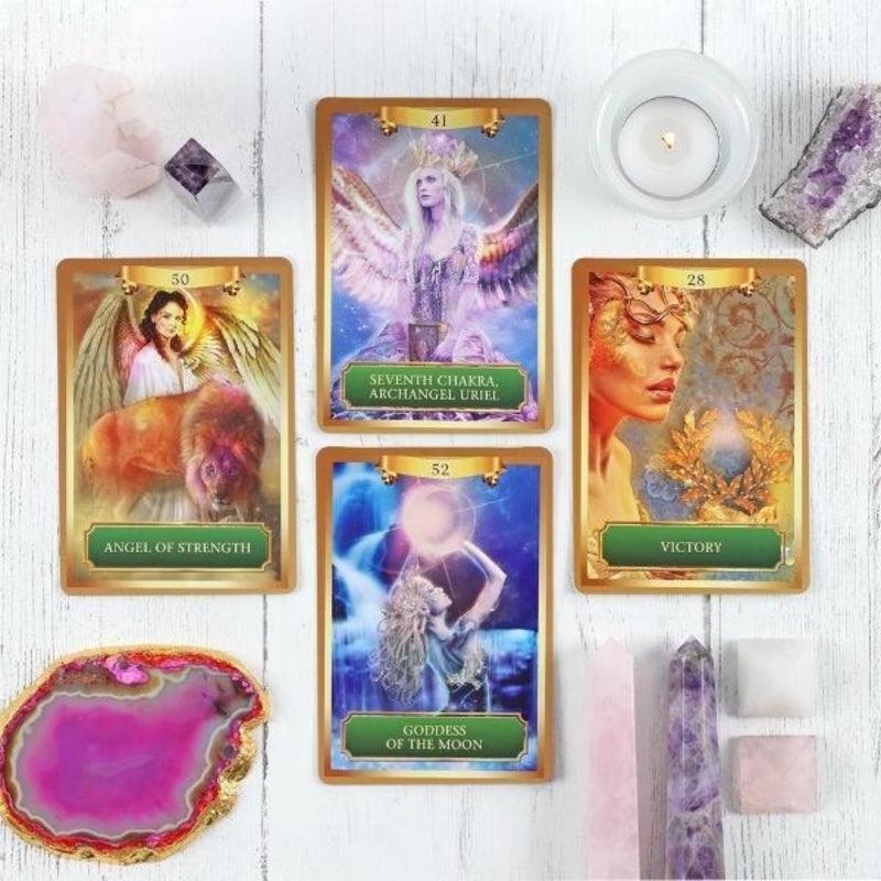 4 energy oracle cards on a white wooden table surrounded by crystals and candles