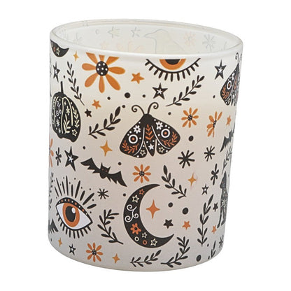 white glass candle with black and orange witchy designs