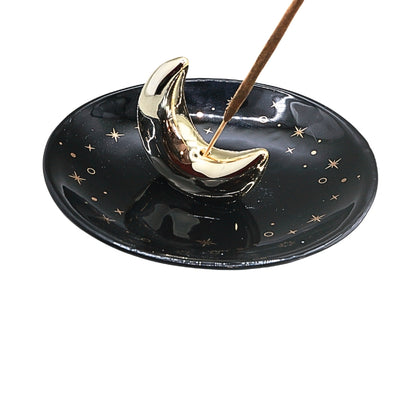A glossy black ceramic dish decorated with small gold stars and a raised metallic gold crescent moon topper, shown on a plain white background.