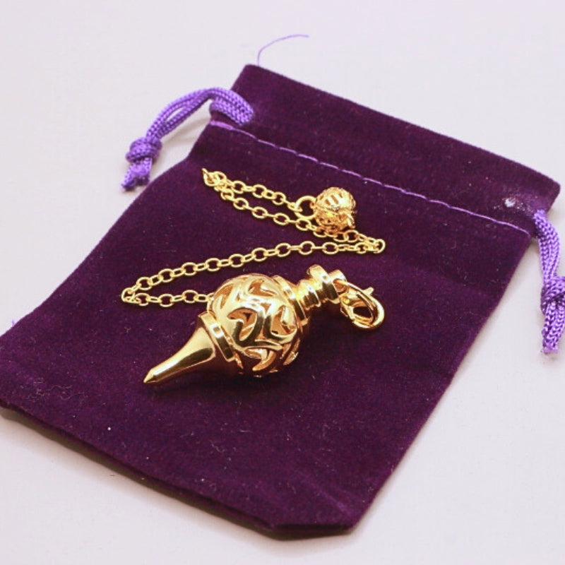 gold pendulum on purple velvet bag