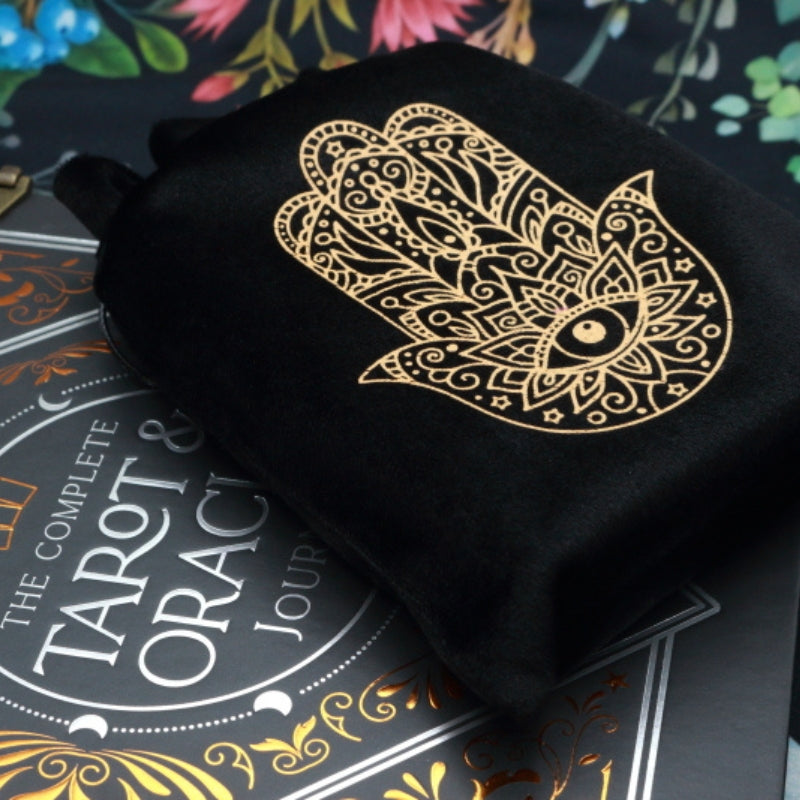 black and gold Hamsa Hand Tarot Bag for Tarot and Oracle Cards on top of a tarot and oracle journal