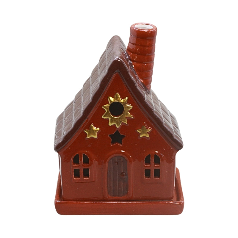 A small decorative house-shaped ceramic container or figurine with a red body, brown roof, red-brown door, and gold sun and star emblems on a plain white background.