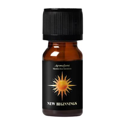 A small amber glass bottle with a black ribbed cap and a black label featuring a yellow and orange sun graphic and the text 'Aromafume' and 'NEW BEGINNINGS'.