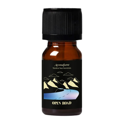 A small amber glass bottle with a black ribbed cap and a black label. The label features a graphic of mountains and a winding road, with the brand name 'Aromafume' and the scent name 'OPEN ROAD' visible.